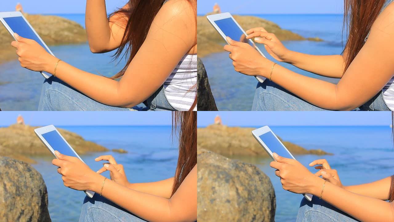 在海边使用平板电脑的特写女人的手