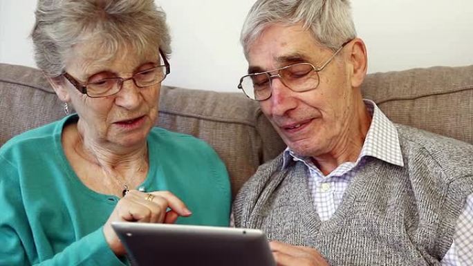 一对70多岁的老夫妇在家里使用数字平板电脑。