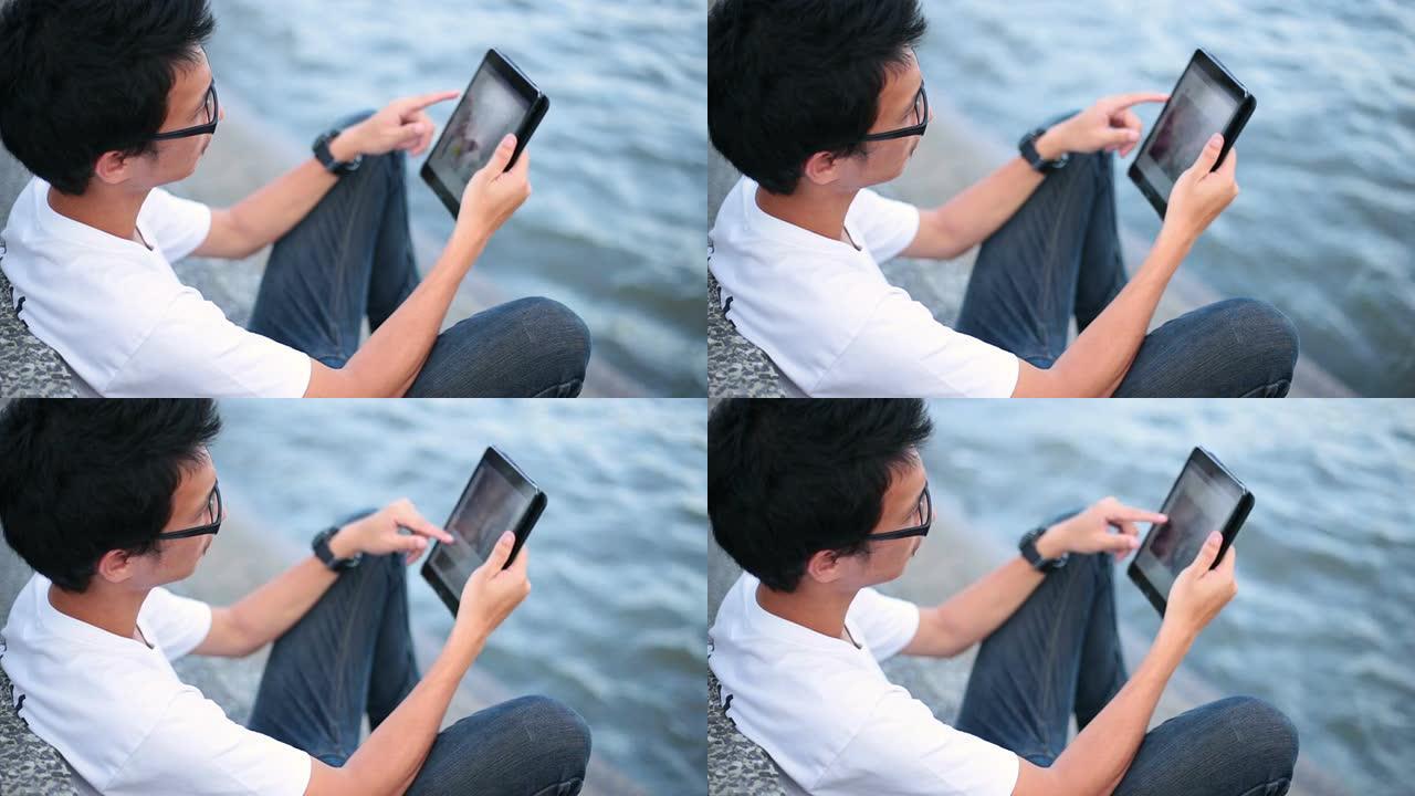 男子在河边的平板电脑上读书