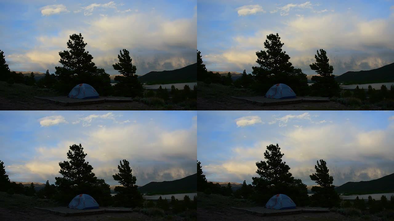 随着太阳的落山和云层营造出高山的光芒，露营帐篷独自站立。
