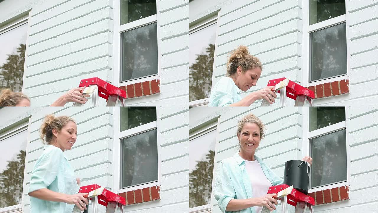 女人爬梯子，准备粉刷房屋外观
