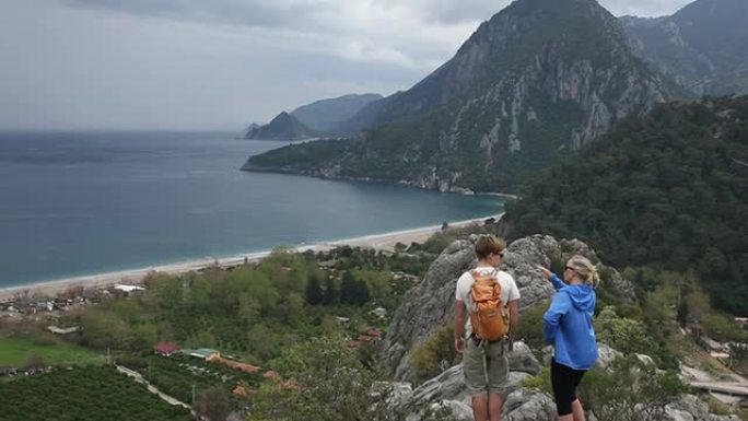 徒步旅行者抵达海面和山脉上方的山脊