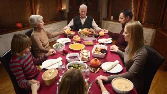 家人在感恩节餐桌上祈祷