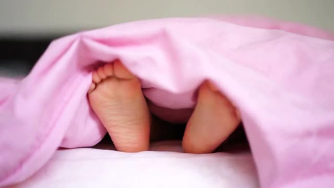 一名亚洲幼童在床上展示双脚