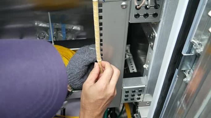 技术工人正在重新布置电信设备机架中的光缆