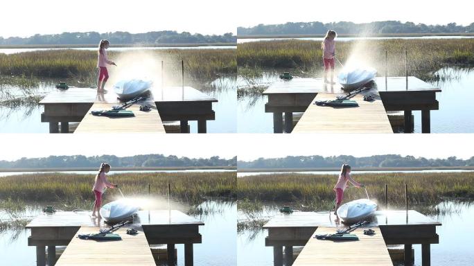 日落时分，一名8岁女孩在码头上喷洒她的皮划艇