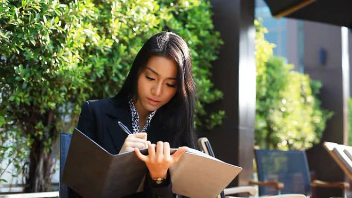 高清：漂亮的亚洲女人在笔记本上记笔记。