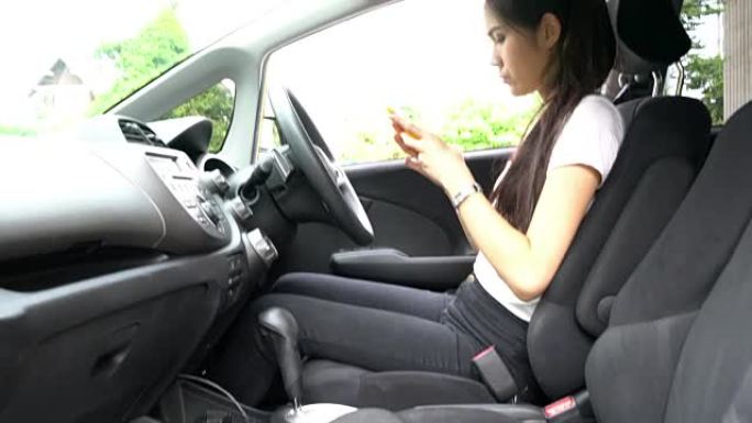 在汽车上使用智能手机的女孩