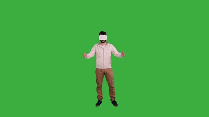戴着虚拟现实眼镜的年轻人在绿色背景上展示了复制空间和拇指