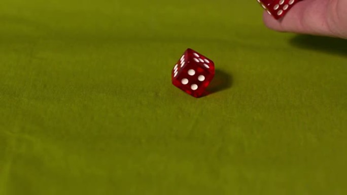 手在绿色桌子上扔两个红色骰子