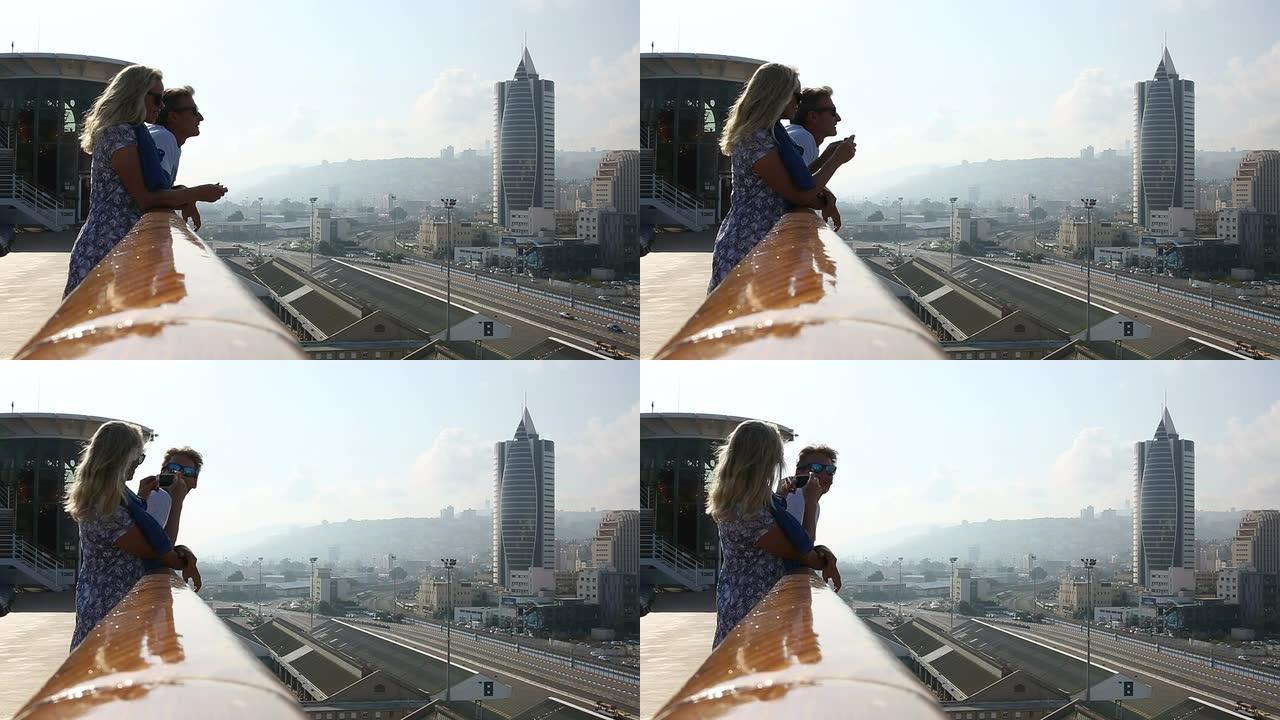 以色列海法，一对夫妇在船栏杆外眺望下面的城市