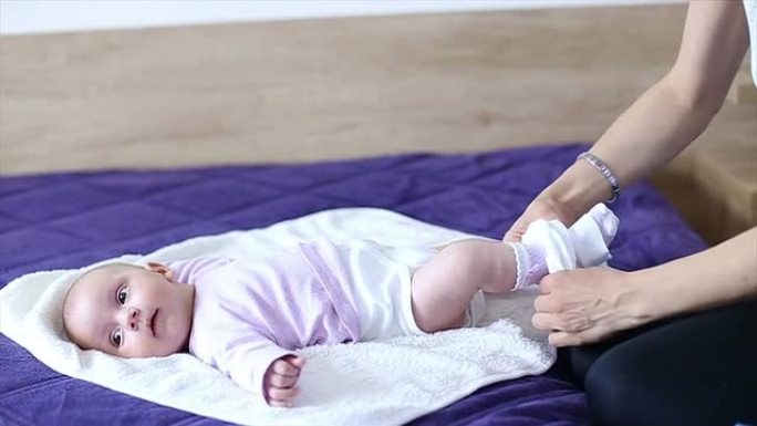 母亲给女儿换尿布躺在床上照料婴儿换尿不湿