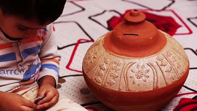小宝贝玩硬币和粘土Gullak (存钱罐)。