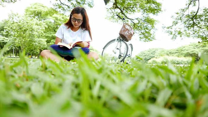 年轻女子坐在公园看书
