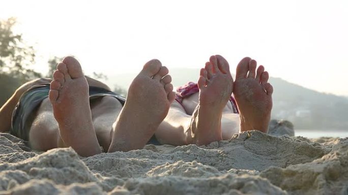 空旷海滩上情侣双脚的细节，从沙滩上看