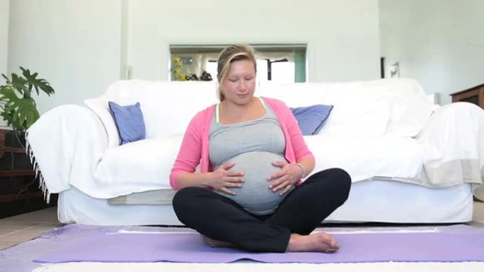 孕妇试图伸展普拉提垫子大肚婆