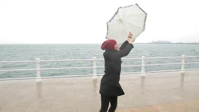 快乐的年轻女子在雨天打着伞跳舞。