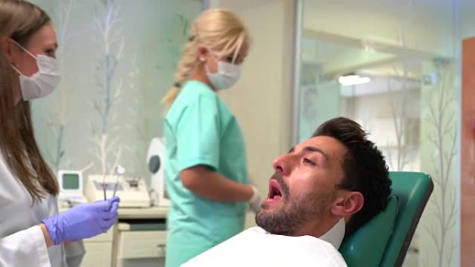 女牙医用口镜检查病人的牙齿。