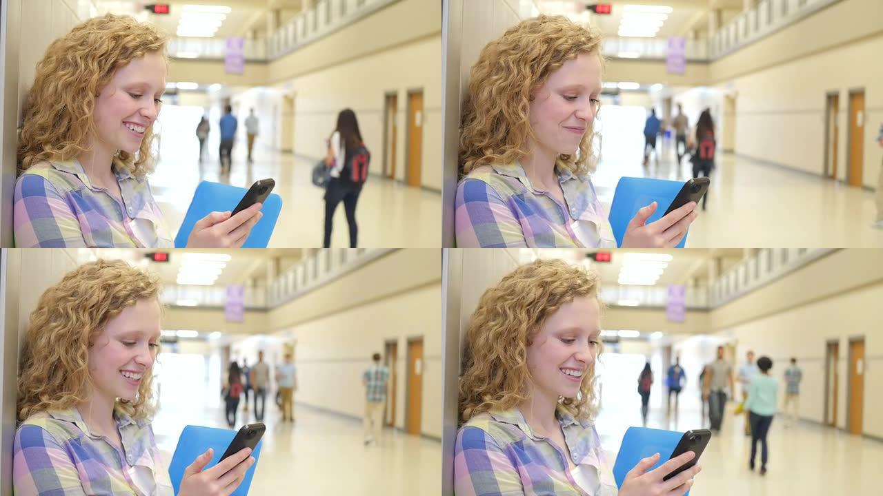 上课前，一名十几岁的女孩在高中走廊用智能手机发短信时大笑