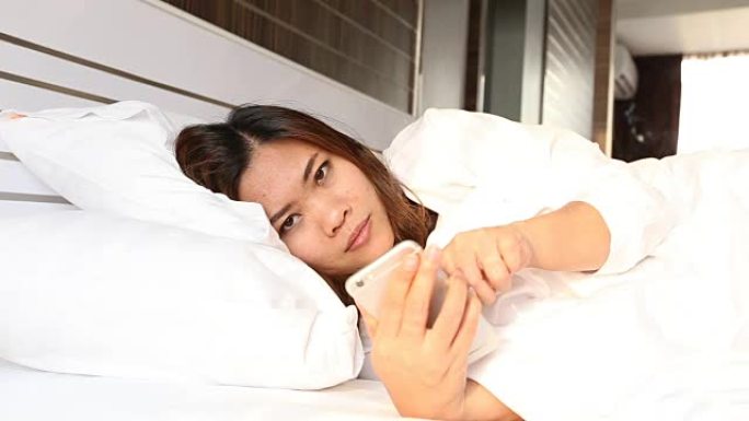 女人躺在床上用智能手机检查社交应用程序，并惊恐地表情