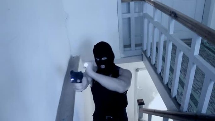 一个戴着面具拿着枪的罪犯在蓝色灯光下