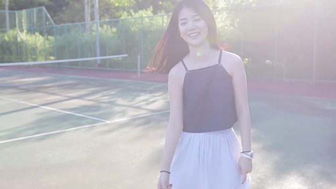 美丽的女孩在网球场上与人造太阳耀斑
