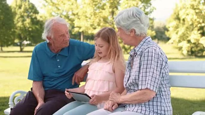 孙女向祖父母展示如何使用平板电脑