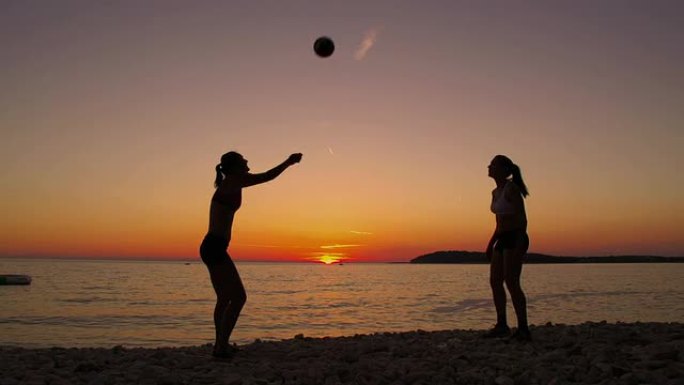 高清：美丽的女人在日落的海滩上打排球