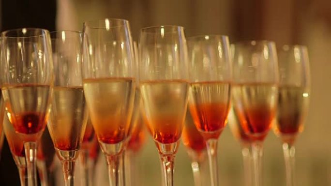 桌子上装饰着花的香槟酒杯的画面。在婚礼庆典上用手摇酒杯。