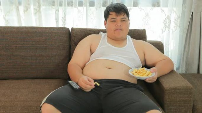 懒洋洋的超重男性坐着吃快餐