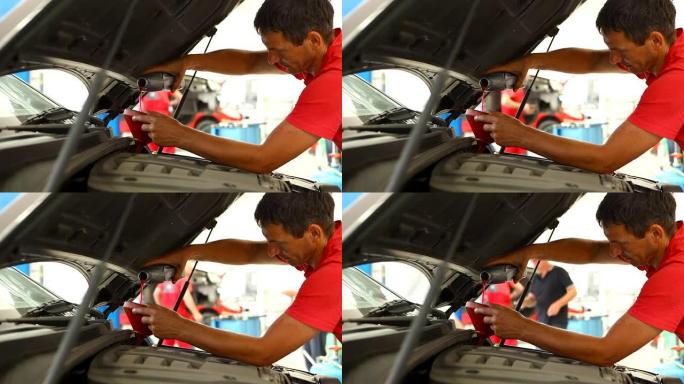 汽车修理工正在倒新的发动机油。