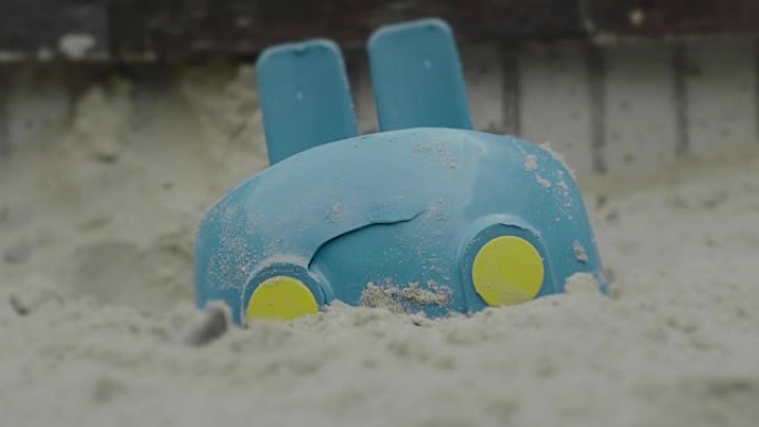 被摧毁的蓝色玩具车在沙滩上，操场