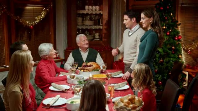 夫妇与家人在圣诞节餐桌上分享喜讯