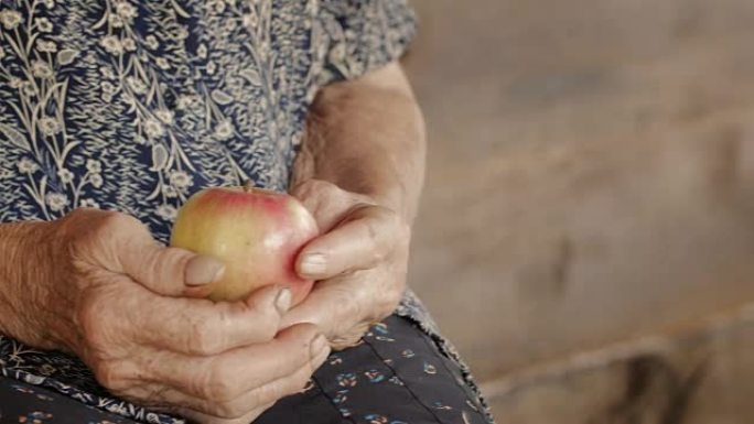 一个伸出援手的小女孩和祖母分享一个苹果。儿童手和高级妇女手的细节。
