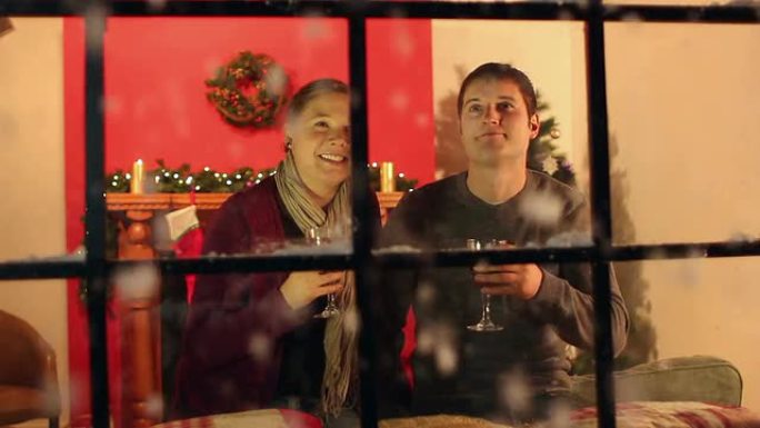一对情侣在圣诞窗口喝热葡萄酒