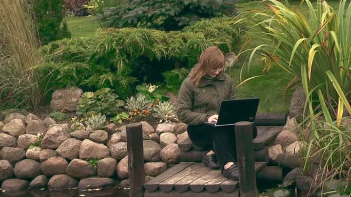 在花园里用笔记本电脑工作的女孩