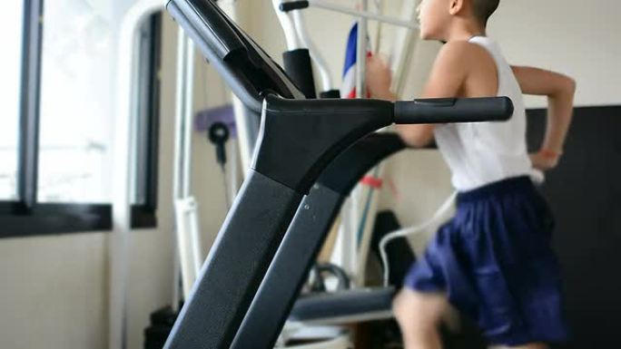 亚洲孩子在健身跑步机上跑步。