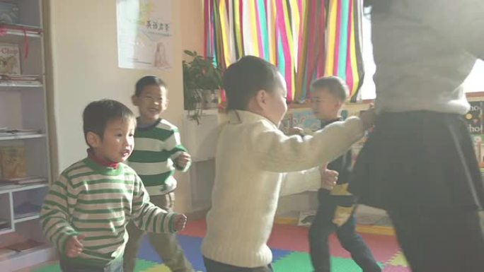亚洲幼儿教师在教室里和孩子们玩游戏，慢动作。