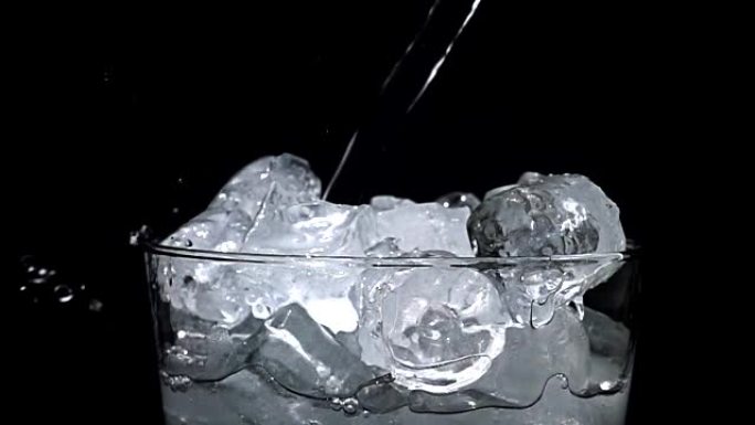在黑色背景上慢动作时，水倒入冰杯中飞溅