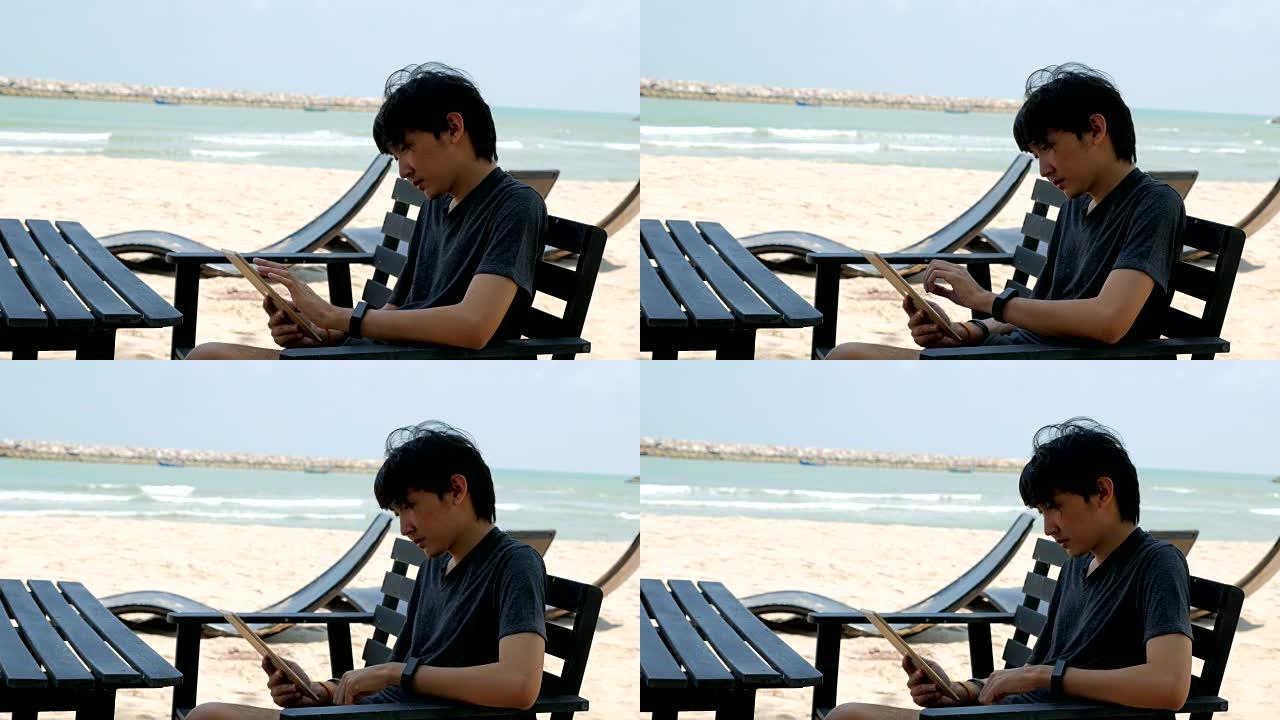 年轻人使用平板电脑，在沙滩上放松