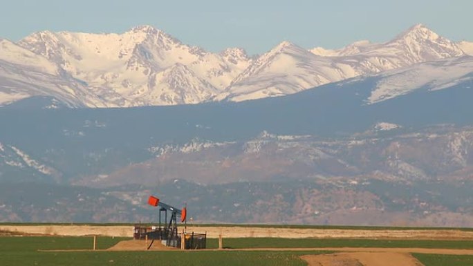 高清视频石油井架和白雪皑皑的落基山脉科罗拉多州韦尔德县