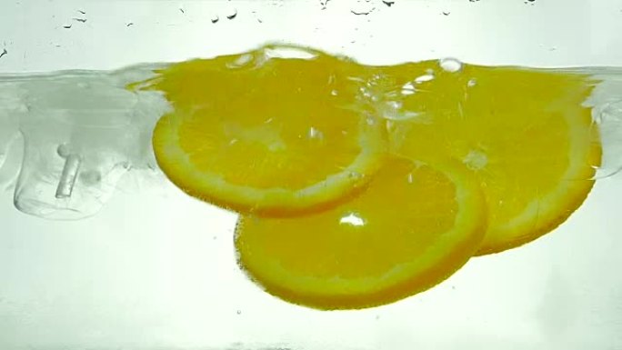 橙片掉进冰水里。特写。慢动作。