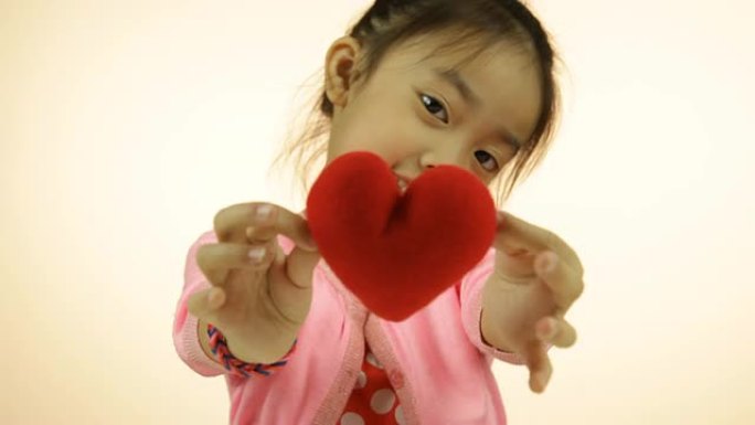 亚洲小女孩展示红心枕头