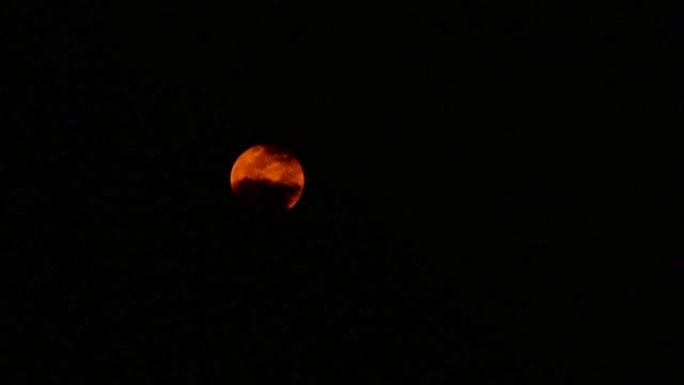 延时，橙色的月亮在云层之间移动。