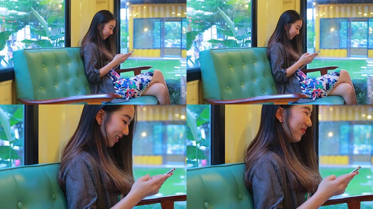 美丽的亚洲女孩在咖啡店里打字手机