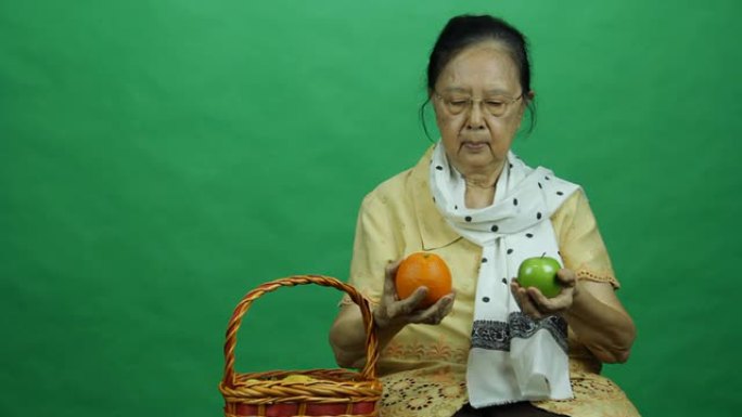 一位老妇人从果篮里拿出橘子