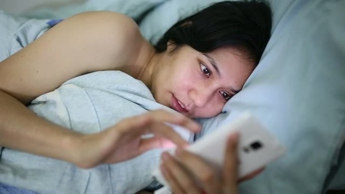 女性在床上使用智能手机