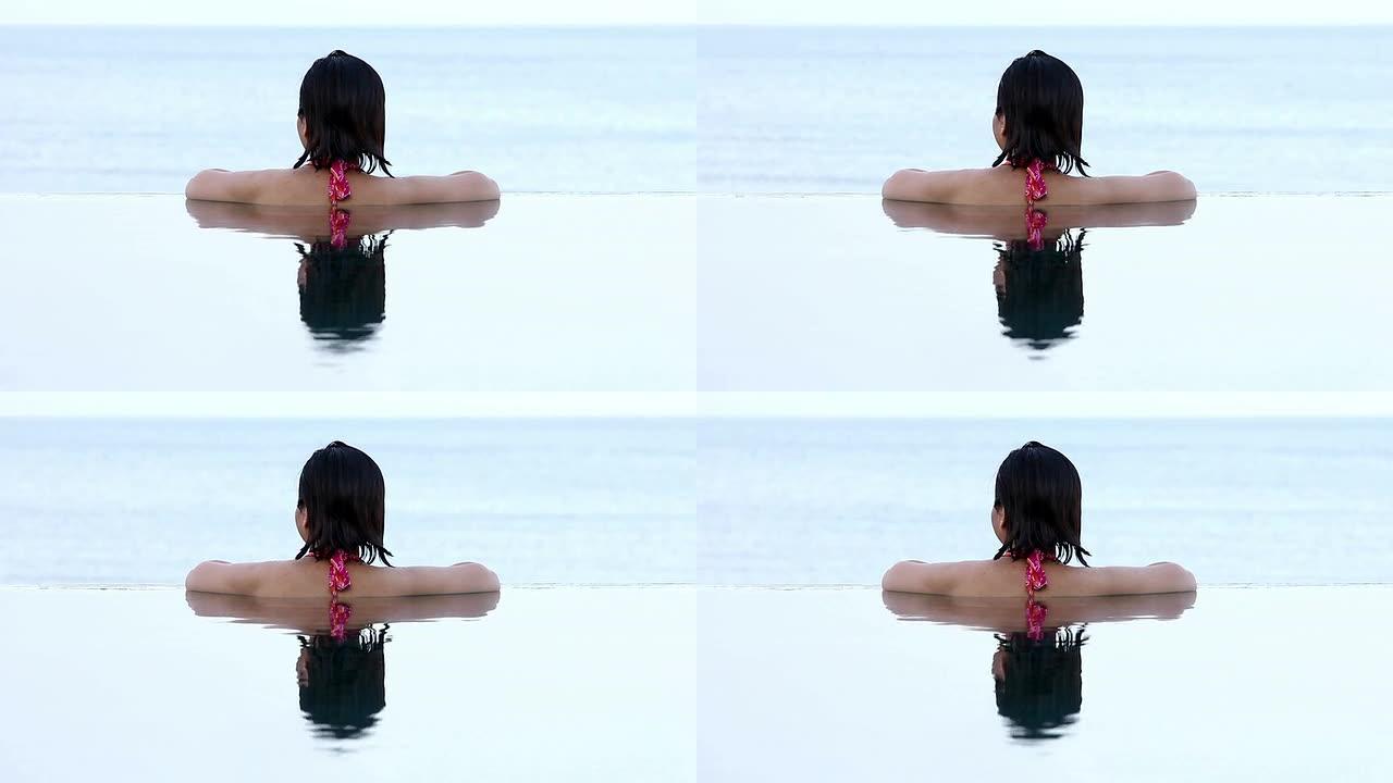亚洲女性从无边泳池望向大海