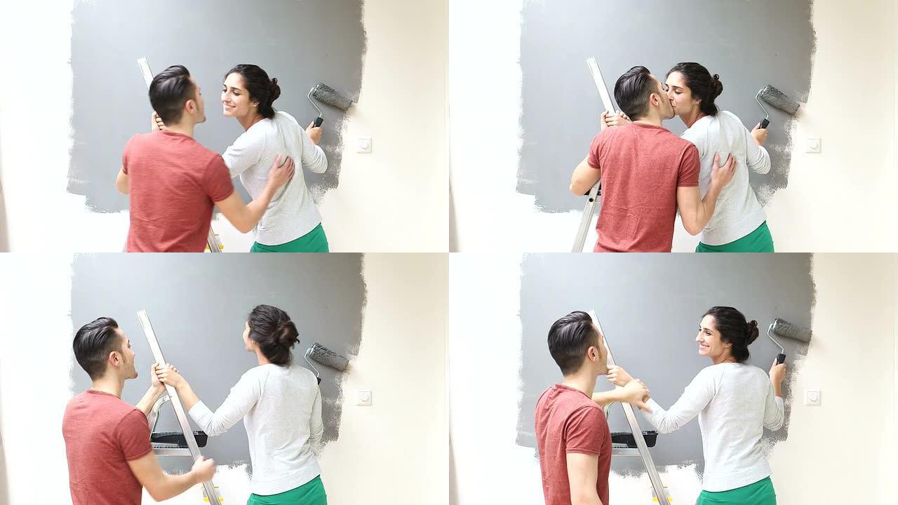 情侣在用油漆滚筒粉刷墙壁时接吻