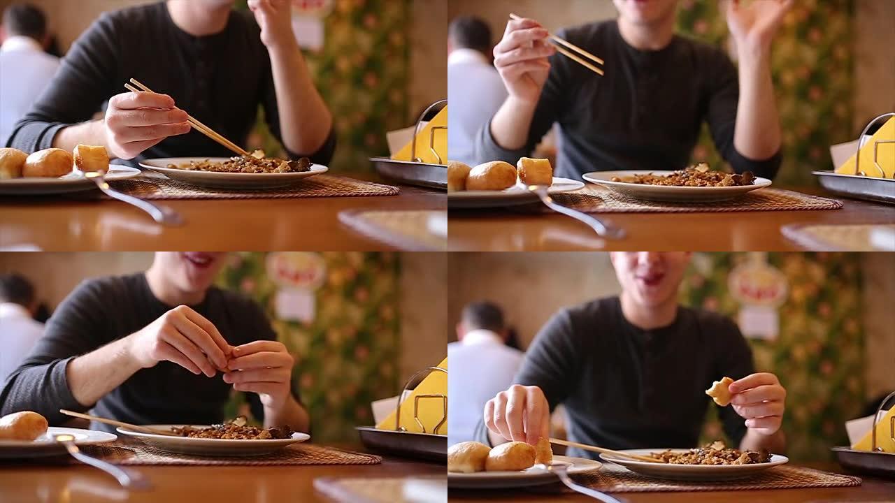 男人在餐厅用筷子吃中国菜